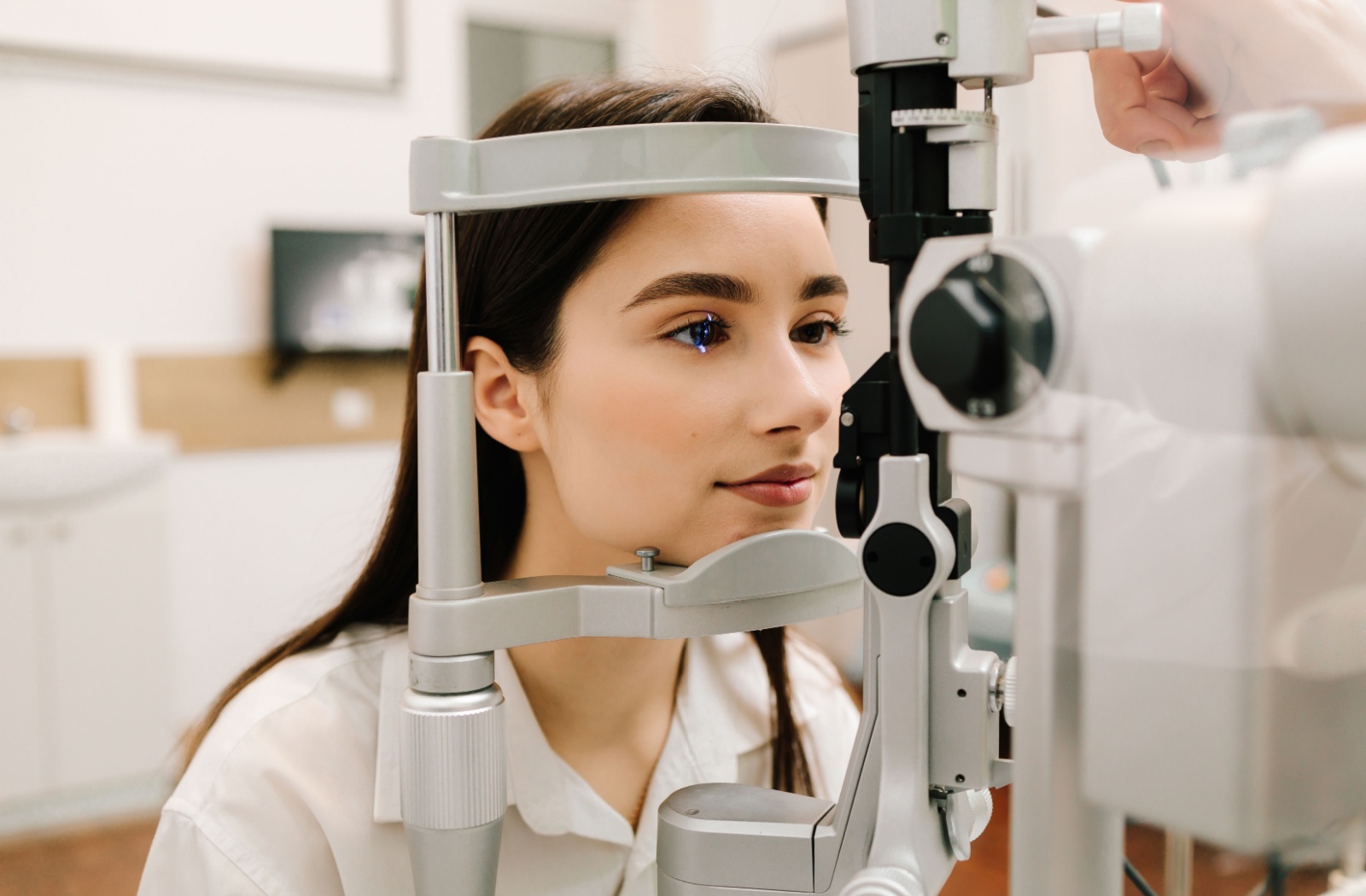 A patient having their eyes examined by an optometrist using a slit lamp.