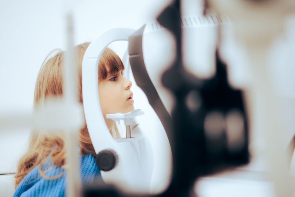 Young child looking through eye examination equipment during a pediatric eye exam.
